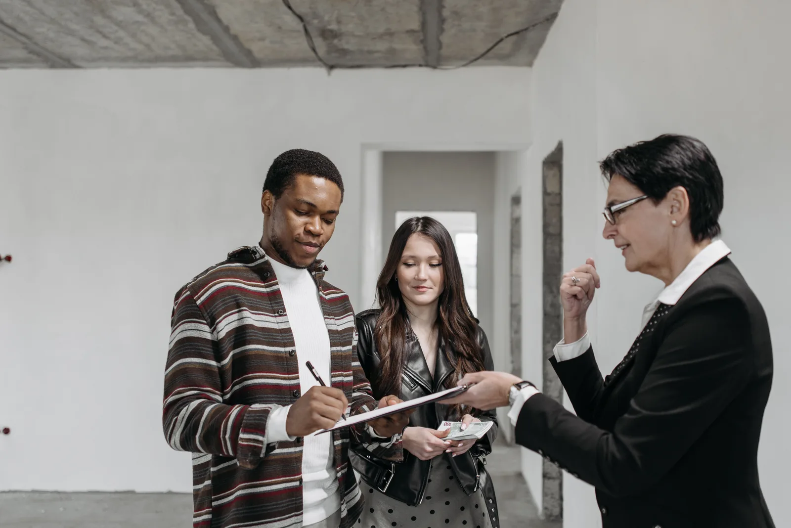 A diverse couple signing documents with a realtor in a new home setting. Where SBA 504 and 7(a) borrower equity really comes from
